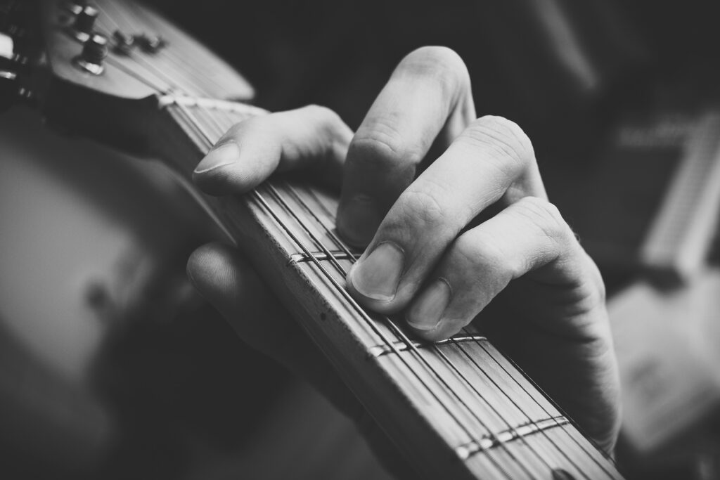 Fingers holding down strings on the neck of a guitar