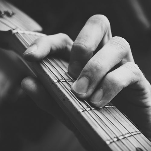 Fingers holding down strings on the neck of a guitar